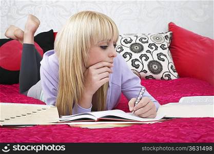 Teenage girl (16-17) lying on bed, writing