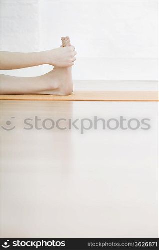 Teenage girl (16-17) stretching leg, low section
