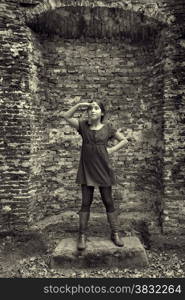 Teenage girl acting as a lady from the past standing in front of the ruin of her castle