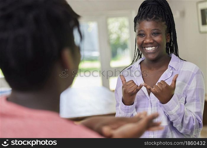 Teenage Girl And Boy Having Conversation Using Sign Language At Home