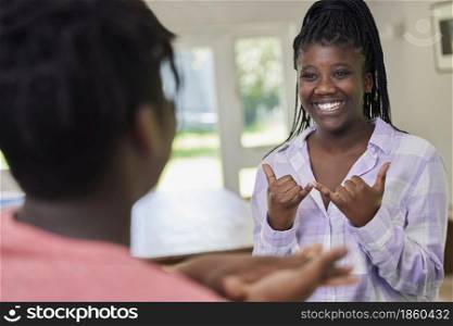 Teenage Girl And Boy Having Conversation Using Sign Language At Home