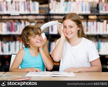 Teenage girl and her brother with books in library. Teenage girl and her brother with books