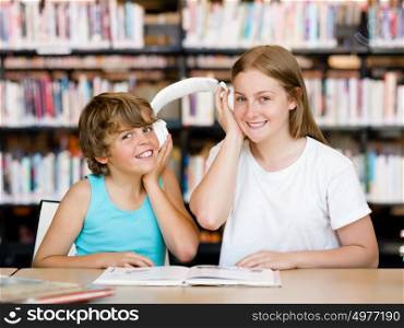 Teenage girl and her brother with books in library. Teenage girl and her brother with books