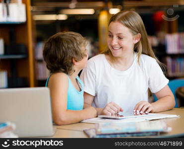 Teenage girl and her brother with books studying in library. Teenage girl and her brother with books