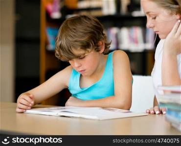 Teenage girl and her brother with books studying in library. Teenage girl and her brother with books