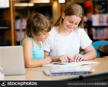 Teenage girl and her brother with books studying in library. Teenage girl and her brother with books