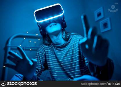 Teenage Girl At Home In Bedroom Wearing Virtual Reality Headset At Night