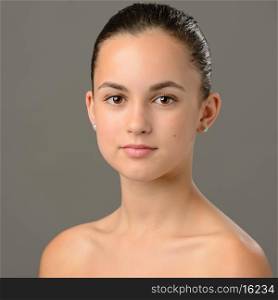 Teenage girl bare shoulders skin care beauty portrait on gray background