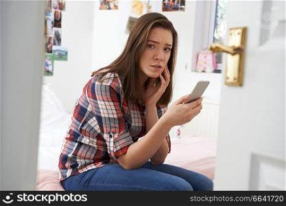 Teenage Girl Being Bullied By Text Message In Bedroom