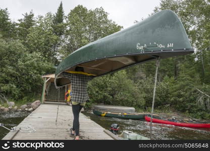 Teenage girl carrying a canoe on her head, BB Camp, Lake of The Woods, Ontario, Canada