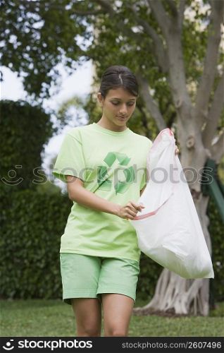 Teenage girl carrying a garbage bag