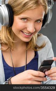 Teenage girl checking her mobile phone smiling looking at camera