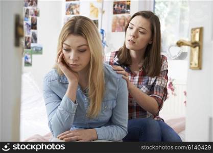 Teenage Girl Comforting Unhappy Friend In Bedroom
