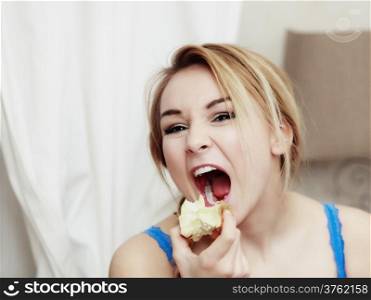 Teenage girl doing fun. Blond woman with braid eating apple healthy fruit. Diet and nutrition. Indoor.