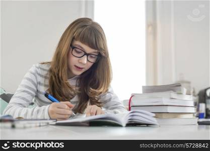 Teenage girl doing homework at table in house