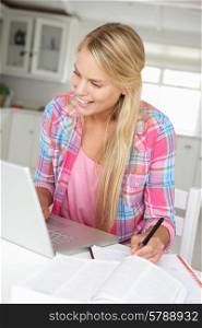 Teenage girl doing homework with laptop