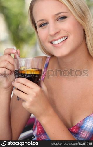 Teenage girl drinking a glass of fruit punch in the sunshine