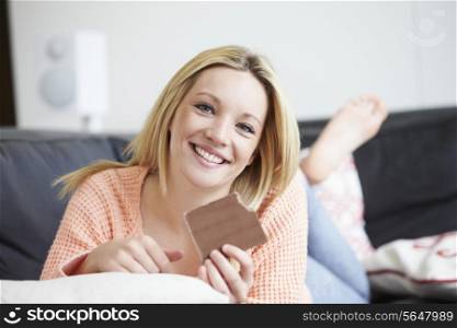 Teenage Girl Eating Bar Of Chocolate At Home