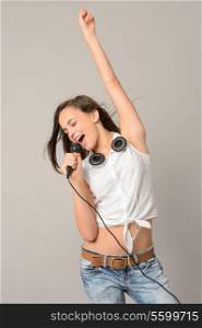 Teenage girl enjoy dancing singing music with microphone on gray background