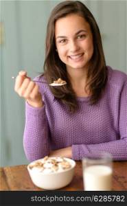 Teenage girl enjoy healthy cereal breakfast smiling at camera