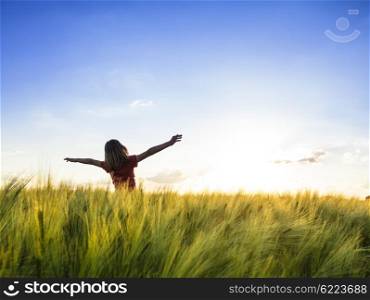 Teenage girl enjoy with sunshine in wheat field. Girl on sunset