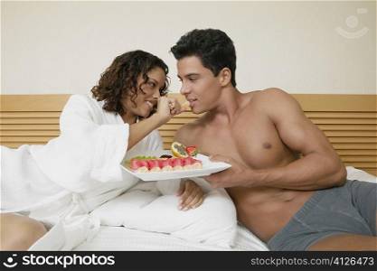 Teenage girl feeding a young man an orange