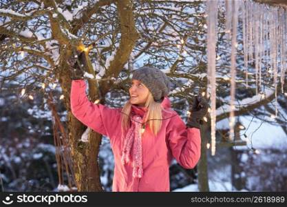 Teenage Girl Hanging Fairy Lights In Tree With Icicles In Foreground