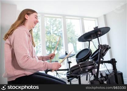 Teenage Girl Having Fun Playing Electronic Drum Kit At Home
