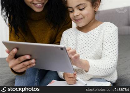 teenage girl helping little sister using tablet online school