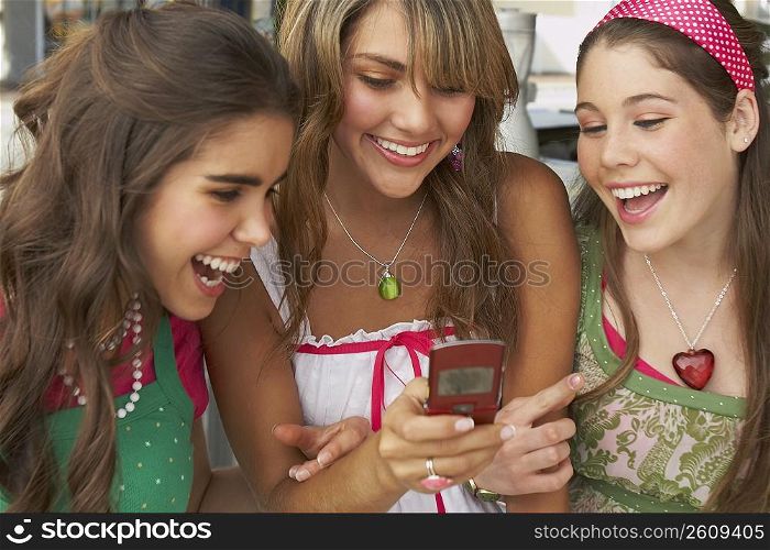 Teenage girl holding a mobile phone and smiling with her friends