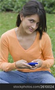 Teenage girl holding a mobile phone in a park