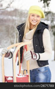 Teenage Girl Holding Sledge In Snowy Landscape