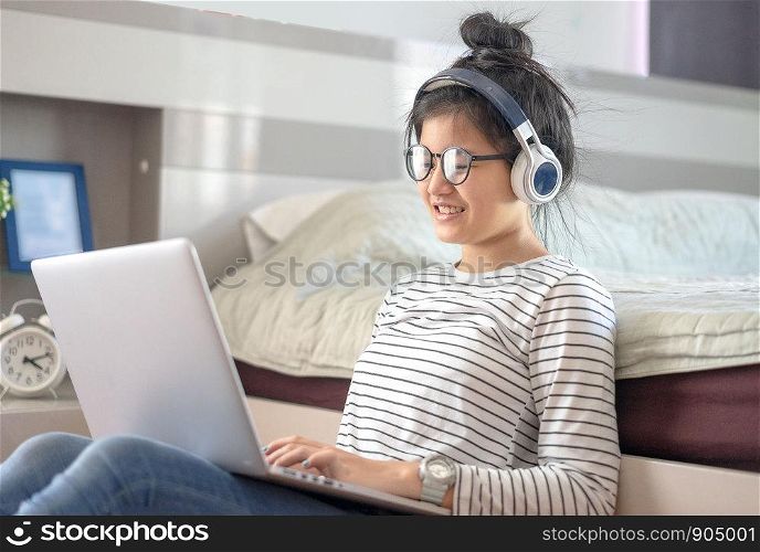 Teenage girl in a bedroom listening to music through his laptop and smart phone.teenager taking online lessons on laptop
