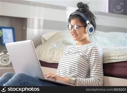 Teenage girl in a bedroom listening to music through his laptop and smart phone.teenager taking online lessons on laptop