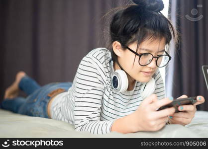 Teenage girl in a bedroom listening to music through his laptop and smart phone.teenager taking online lessons on laptop