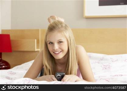 Teenage Girl In Bedroom With Mobile Phone
