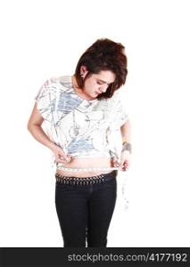 Teenage girl in black jeans and long brown hair measuring her waist,standing for white background.