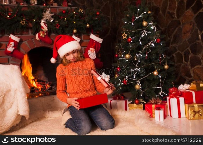 Teenage girl in christmas decorated room open a giftbox