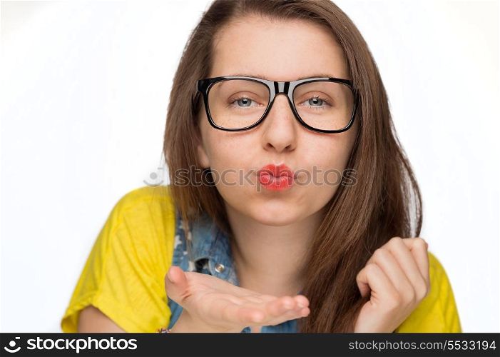 Teenage girl in geek glasses blowing kiss on white background