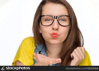 Teenage girl in geek glasses blowing kiss on white background