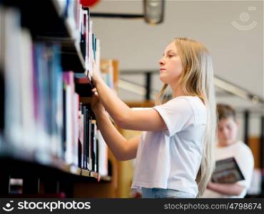 teenage girl in library choosing books. Teenage girl in library
