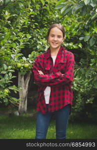 Teenage girl in red checkered shirt posing at apple garden