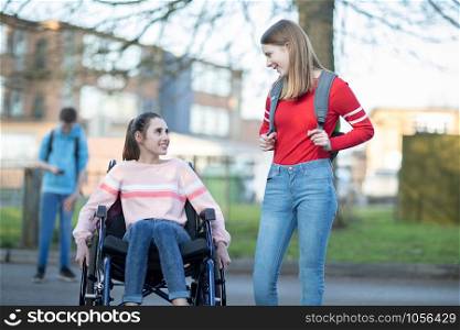 Teenage Girl In Wheelchair Talking With Friend As They Leave High School