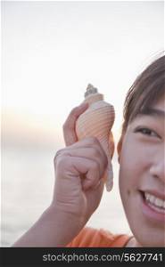 Teenage girl listening to seashell, close up