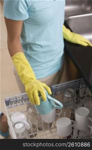 Teenage girl loading dishes into a dishwasher