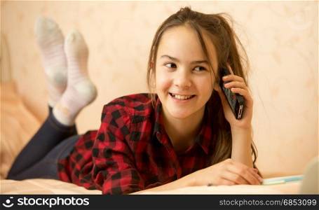 Teenage girl lying in bedroom and talking by phone