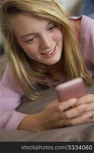 Teenage Girl Lying In Bedroom Using Mobile Phone