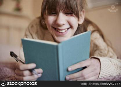 Teenage Girl Lying On Bed At Home Writing In Diary Or Journal