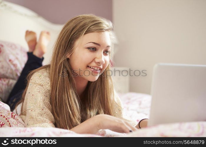 Teenage Girl Lying On Bed Using Laptop