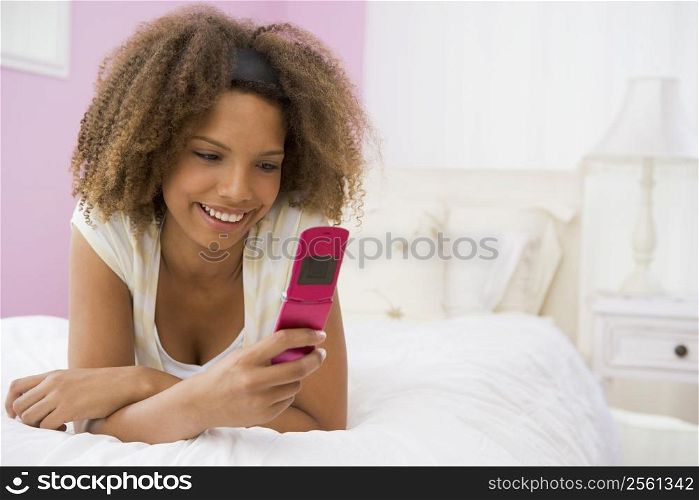 Teenage Girl Lying On Bed Using Mobile Phone